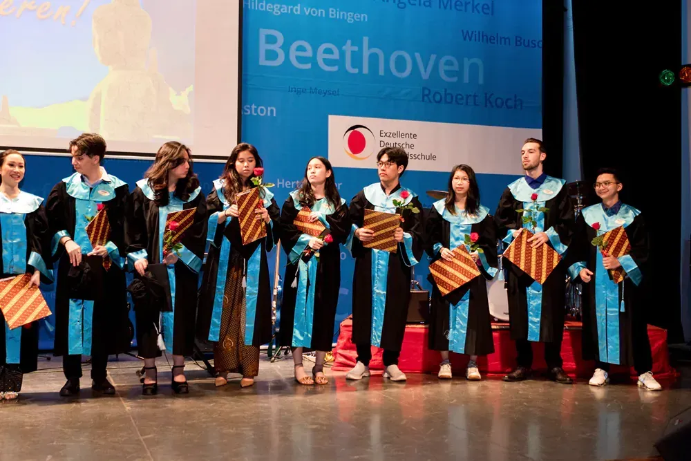 A group of people are standing on a stage in front of a beethoven sign.