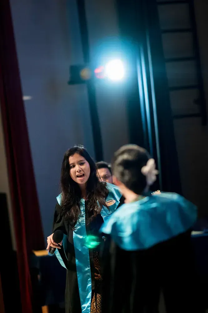 A woman in a blue gown is standing next to a man in a black robe.
