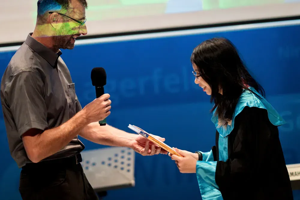 A man is giving a certificate to a woman in a graduation gown