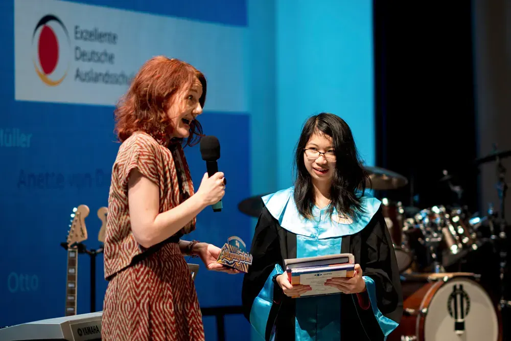 A woman in a graduation cap and gown is talking to another woman