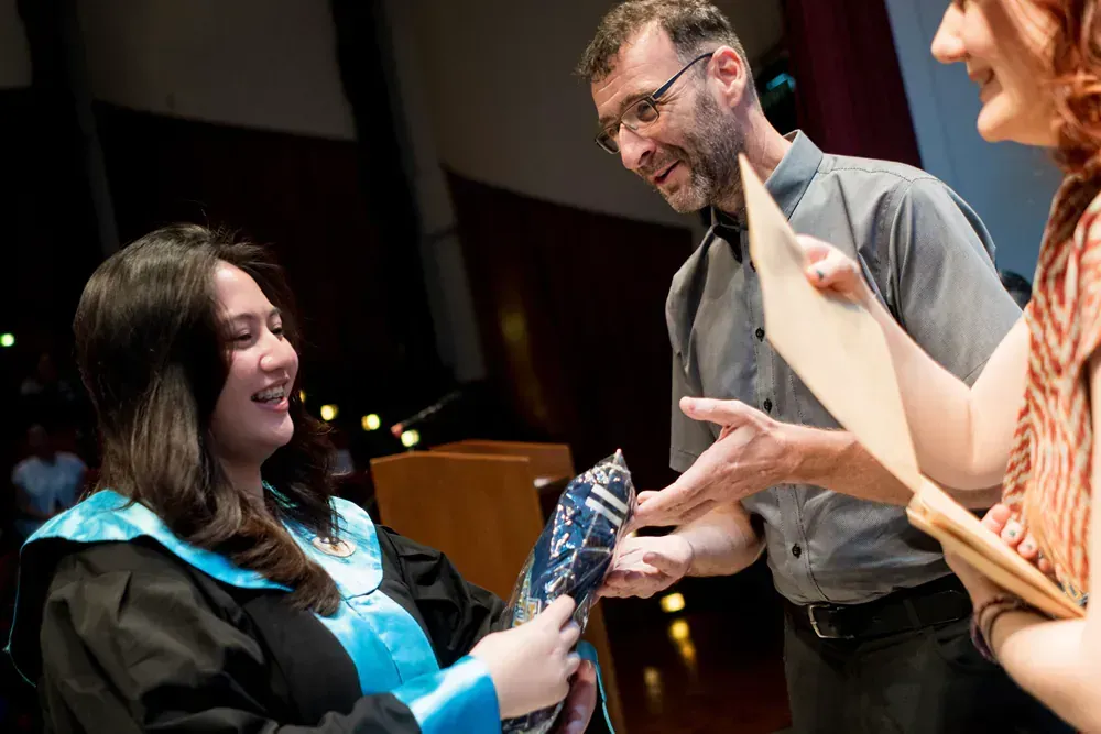 A woman in a graduation cap and gown is receiving a diploma from a man.
