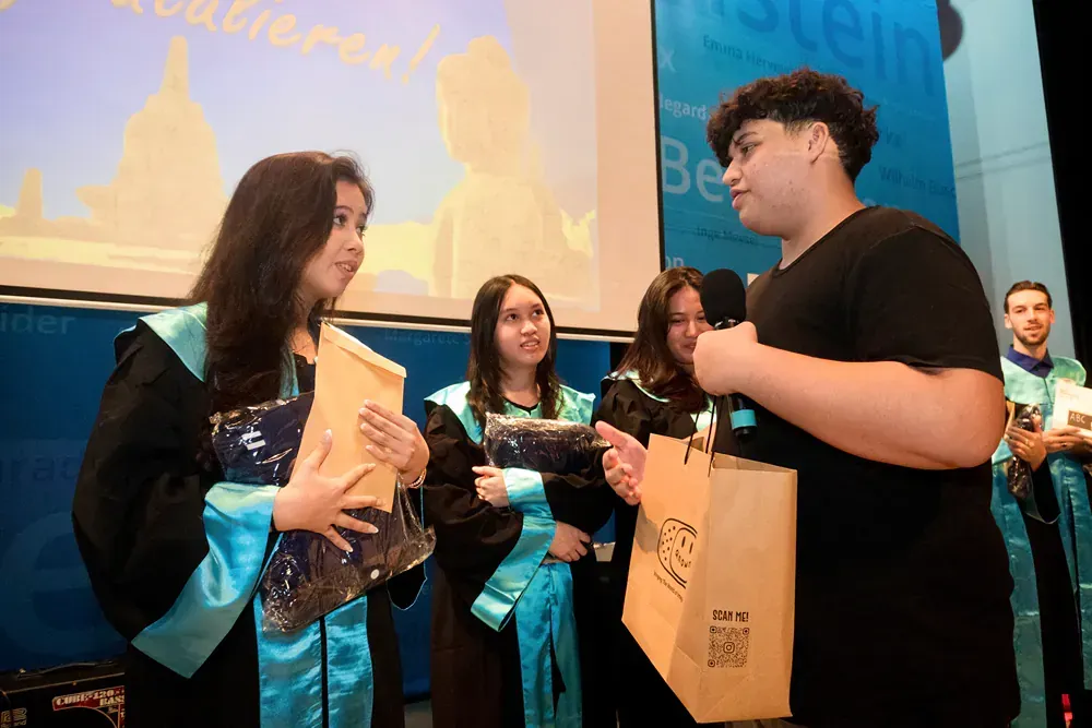A group of people in graduation gowns are standing next to each other on a stage.