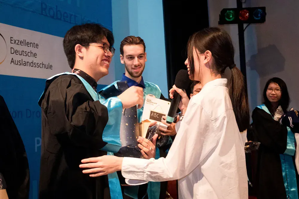 A woman is giving a man a diploma at a graduation ceremony.