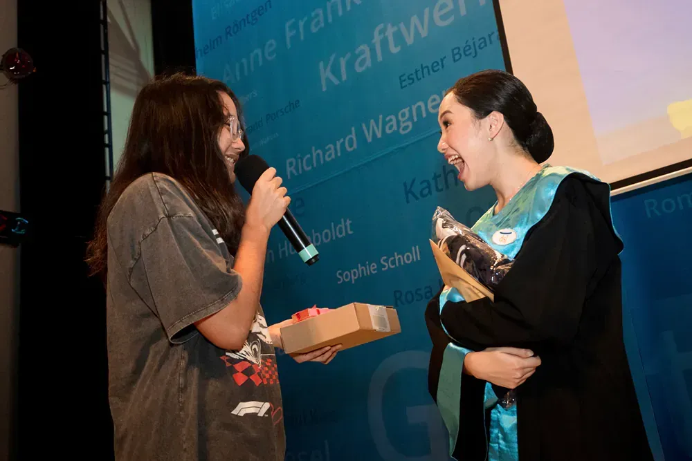 A woman is giving a gift to another woman while holding a microphone.