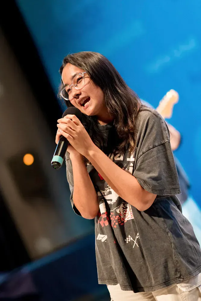 A young woman is singing into a microphone on a stage.