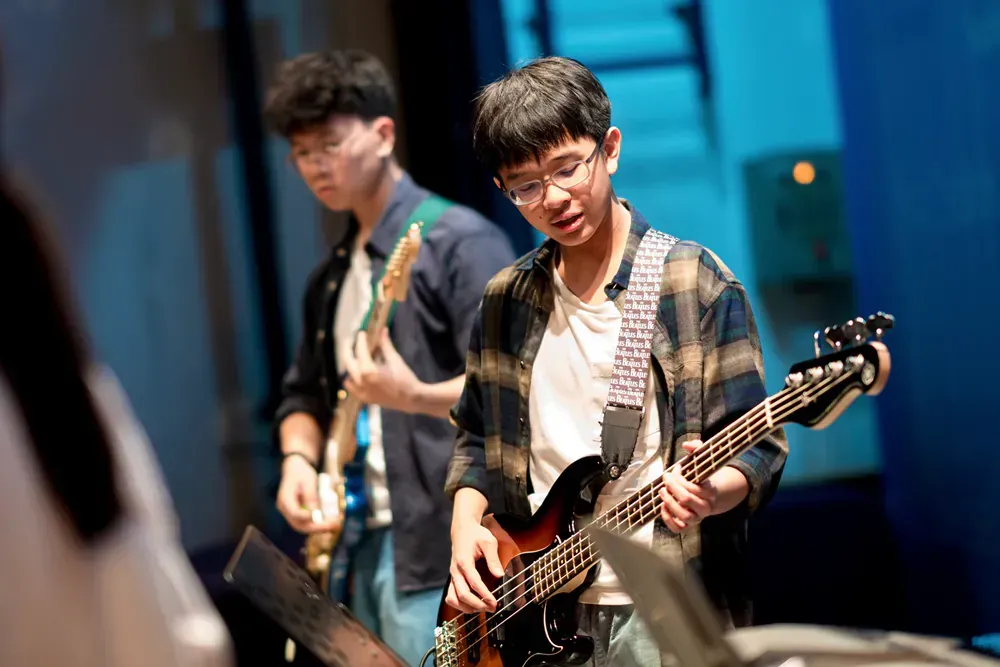 Two young men are playing guitars on a stage.