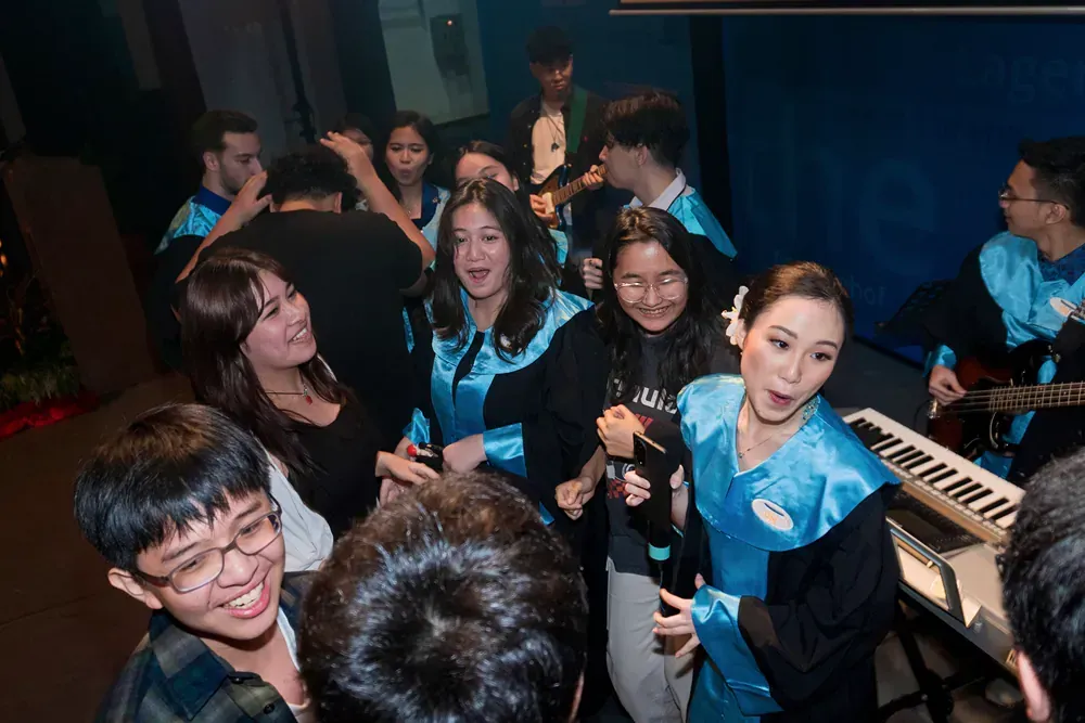 A group of people are standing around a piano in a dark room.