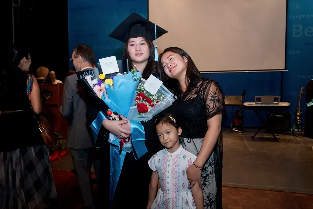 A woman in a graduation cap and gown is holding a bouquet of flowers.