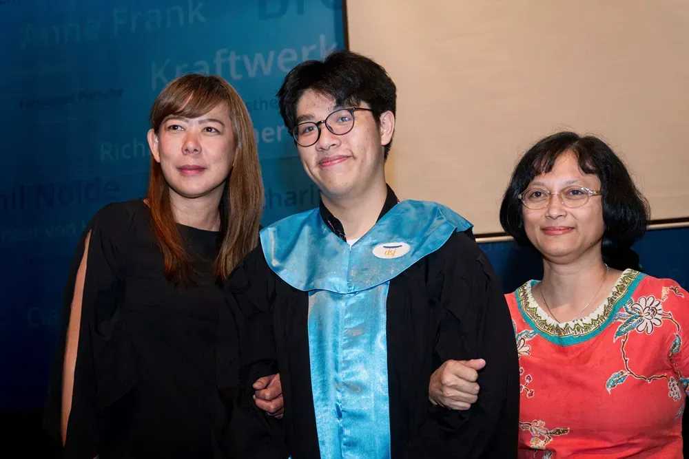 A man in a graduation cap and gown is posing for a picture with two women.