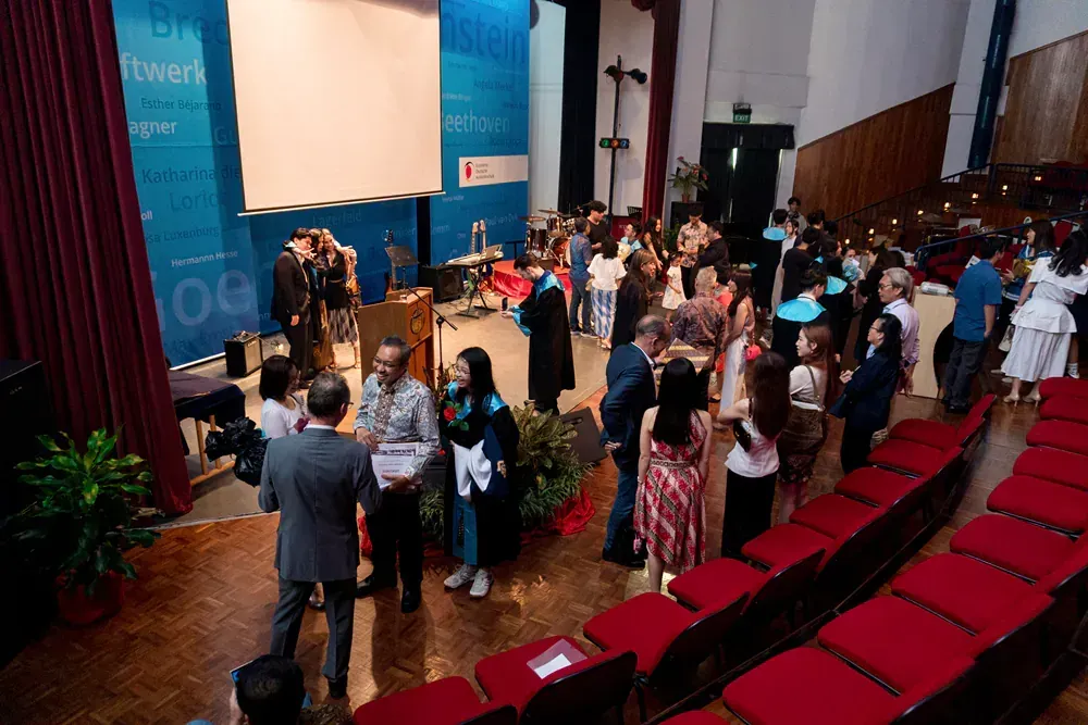 A group of people are standing in a large auditorium.