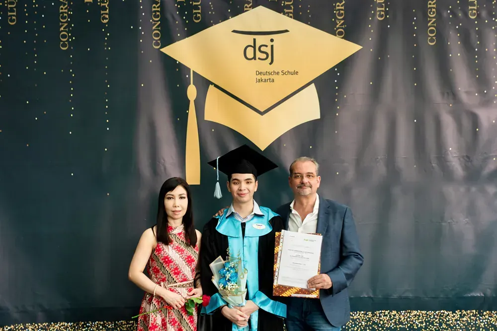 A man and a woman are standing next to a man in a graduation cap and gown.