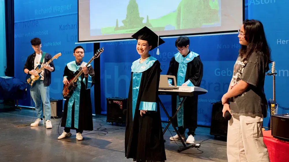 A group of people in graduation gowns are standing on a stage.