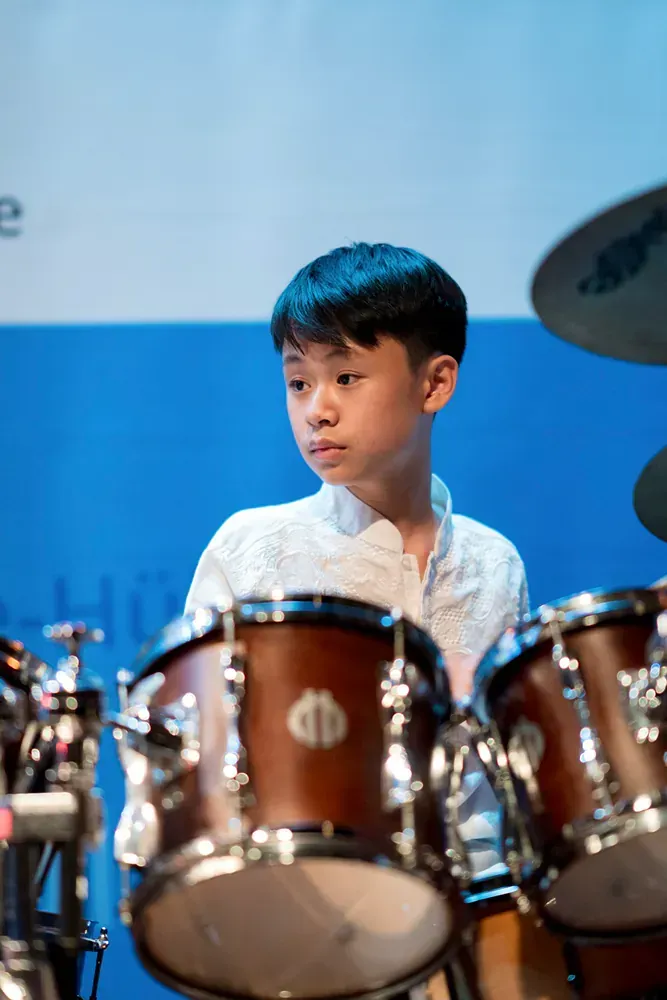 A young boy is playing drums on a stage.