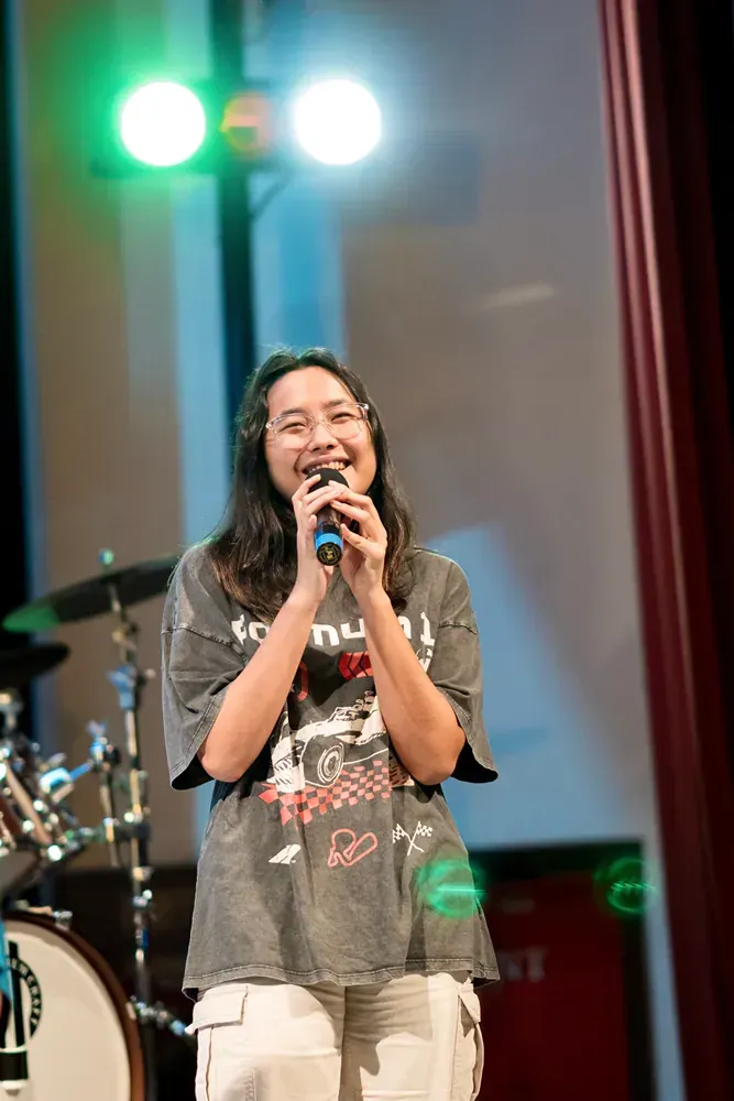 A young woman is singing into a microphone on a stage.