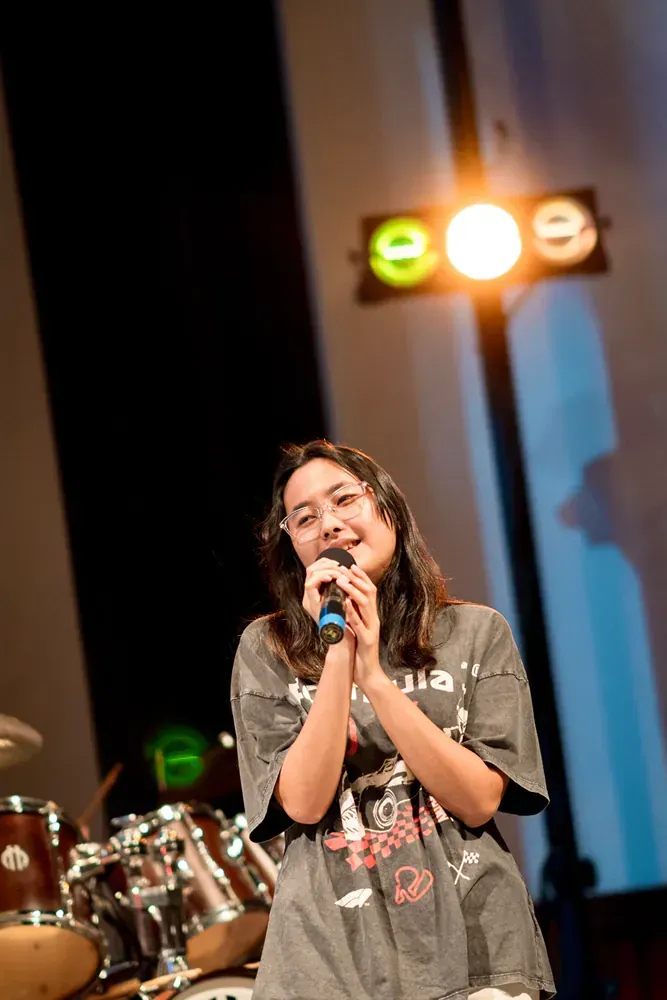 A woman is singing into a microphone on a stage.