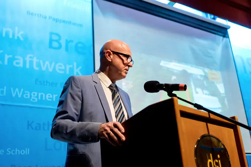 A man in a suit and tie is standing at a podium giving a speech.