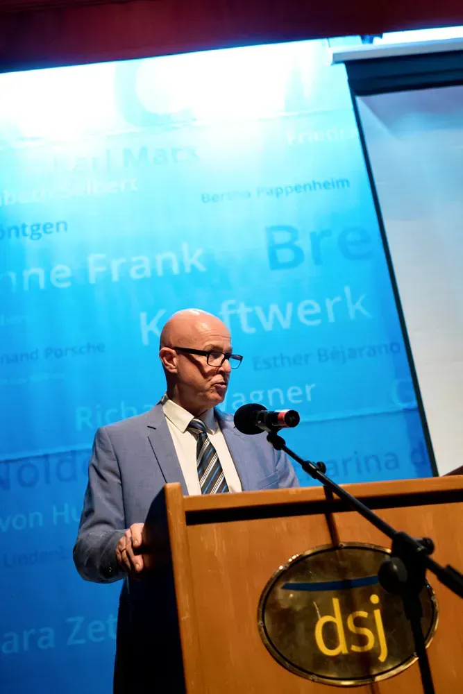 A man in a suit and tie is standing at a podium giving a speech