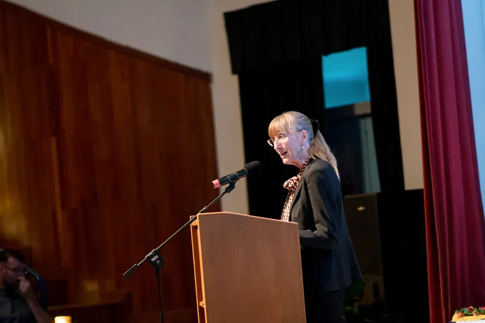 A woman is standing at a podium speaking into a microphone.