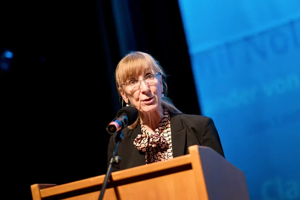 A woman is standing at a podium speaking into a microphone.