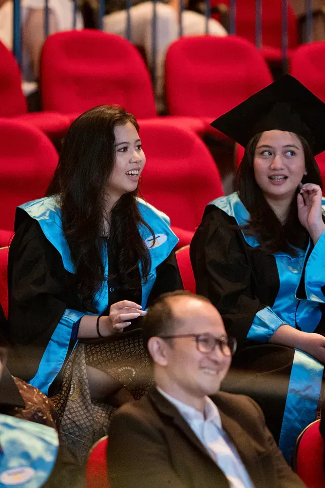 A group of graduates are sitting in a auditorium.