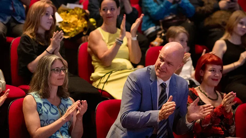 A group of people are sitting in a theater applauding.