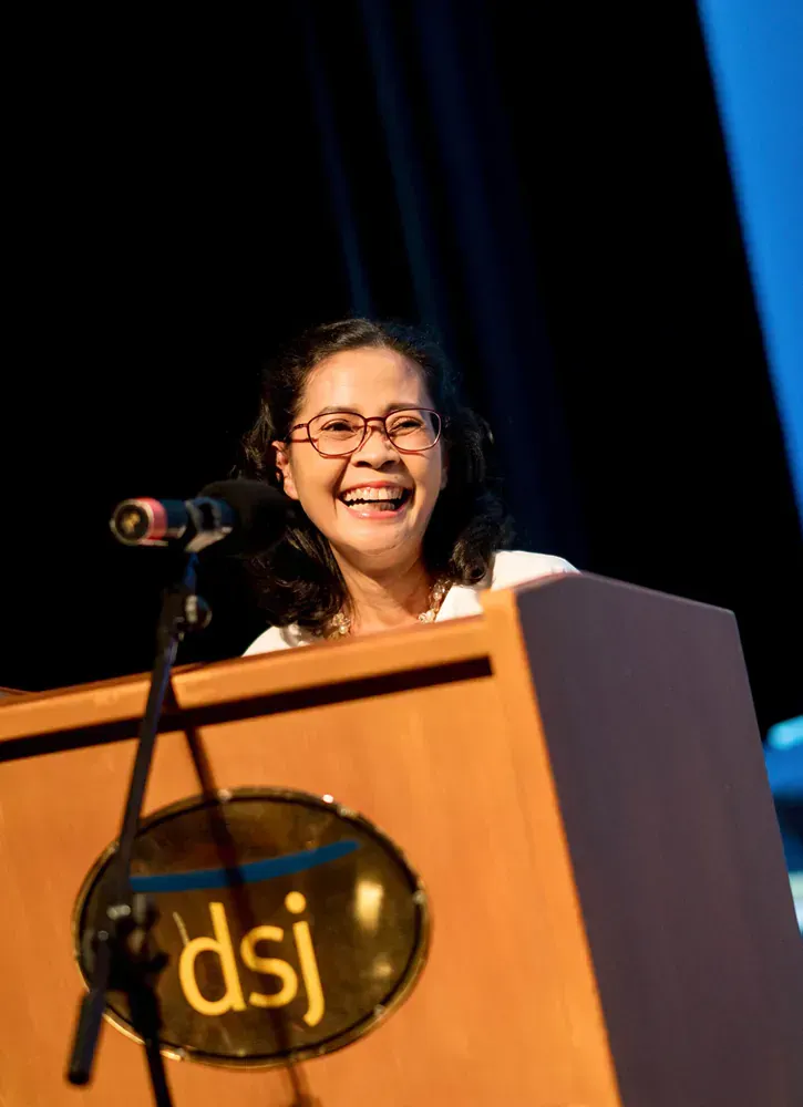 A woman stands behind a podium that says dsj on it