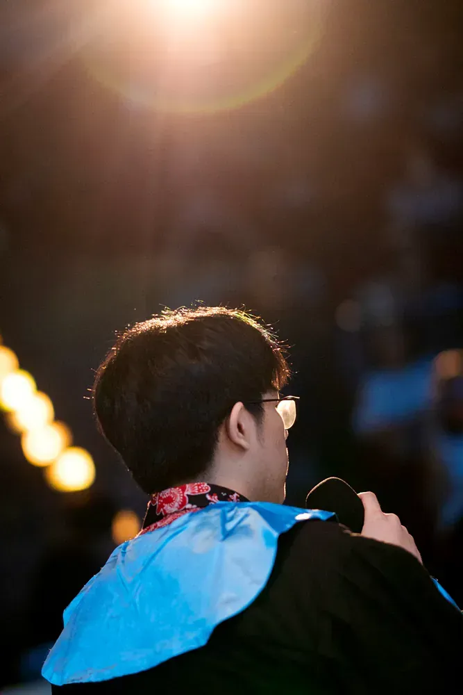 A man wearing glasses is holding a microphone in a dark room.