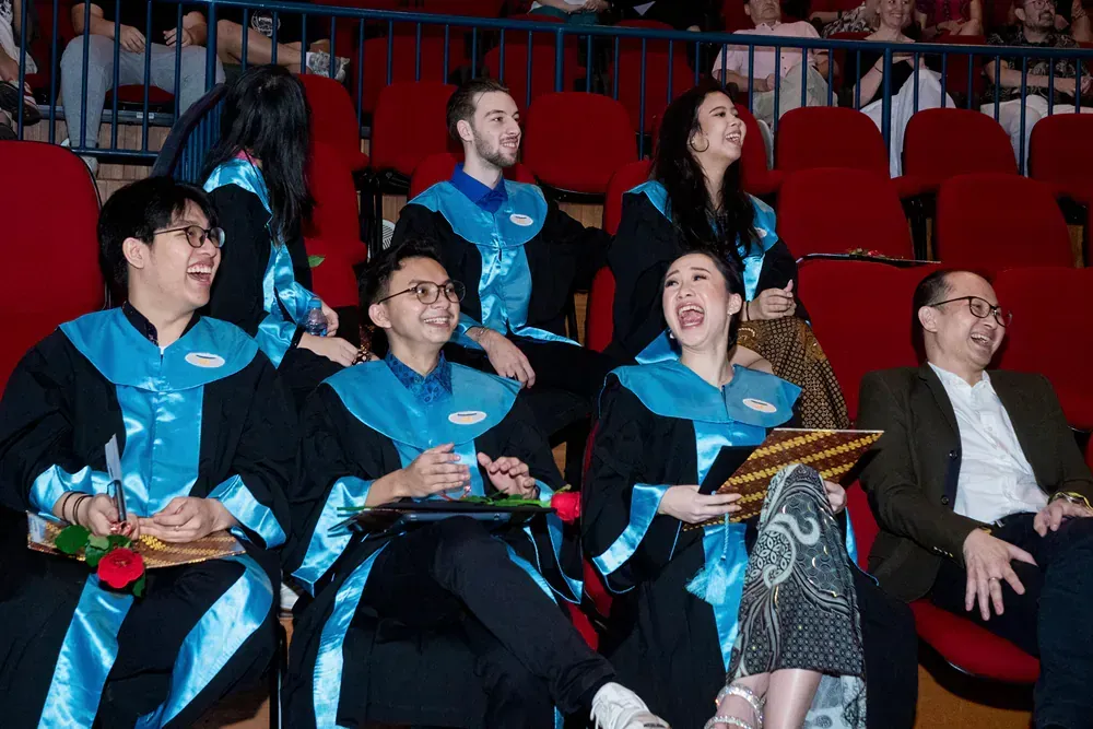 A group of people in graduation gowns are sitting in a stadium.
