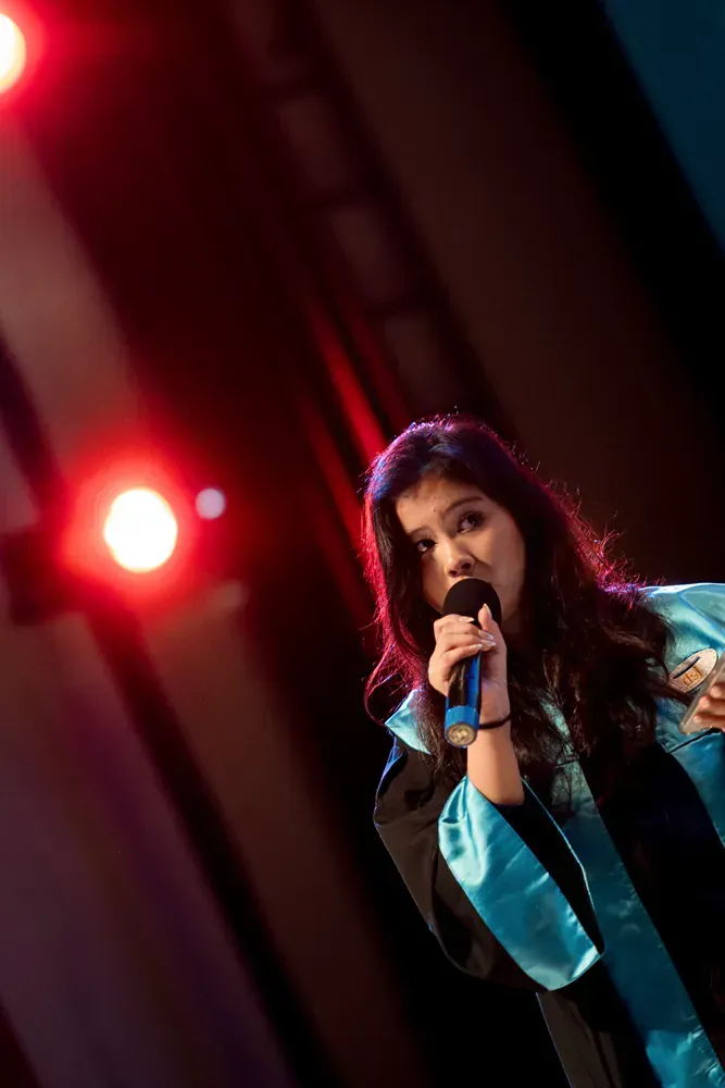 A woman is singing into a microphone on a stage.