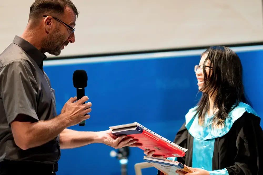 A man is giving a diploma to a woman in a graduation gown.