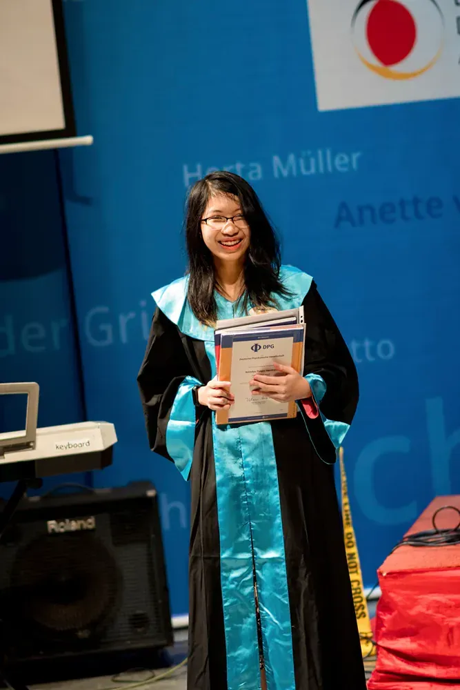 A woman in a graduation gown is holding a book.
