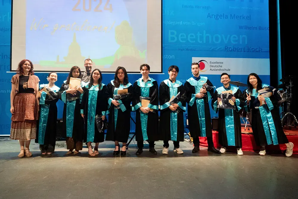 A group of people are standing on a stage in front of a screen that says beethoven