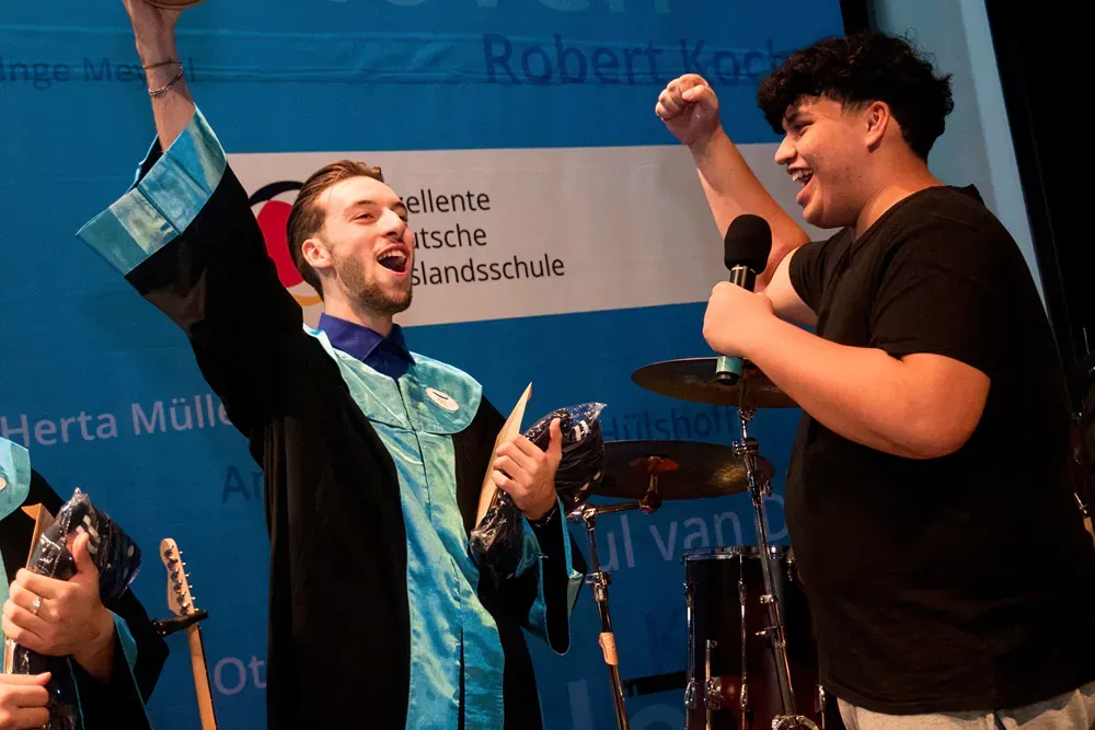 A man in a graduation cap and gown is holding a microphone