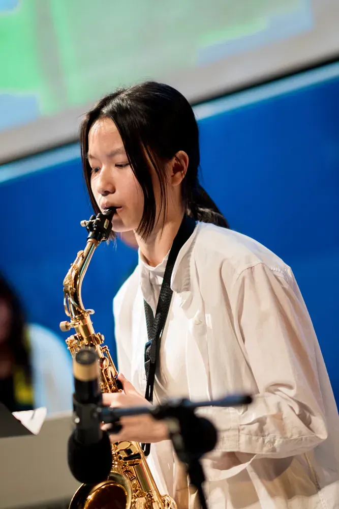 A young woman is playing a saxophone in front of a microphone.