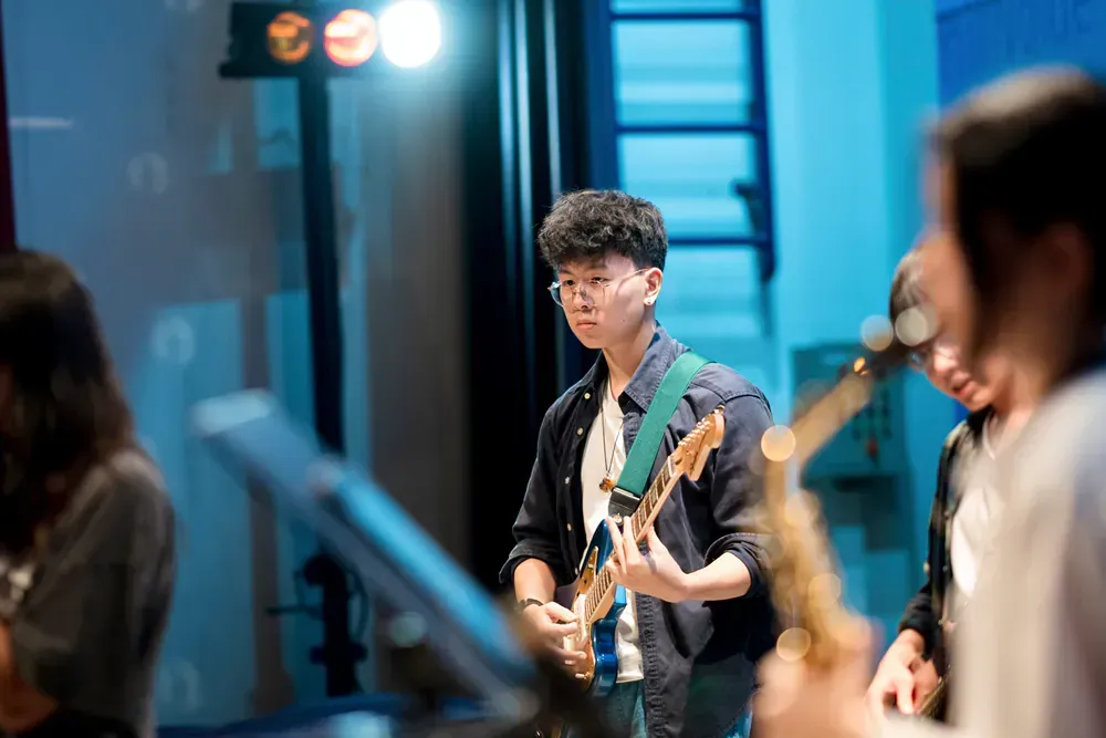 A man is playing a guitar and a woman is playing a saxophone in a band.