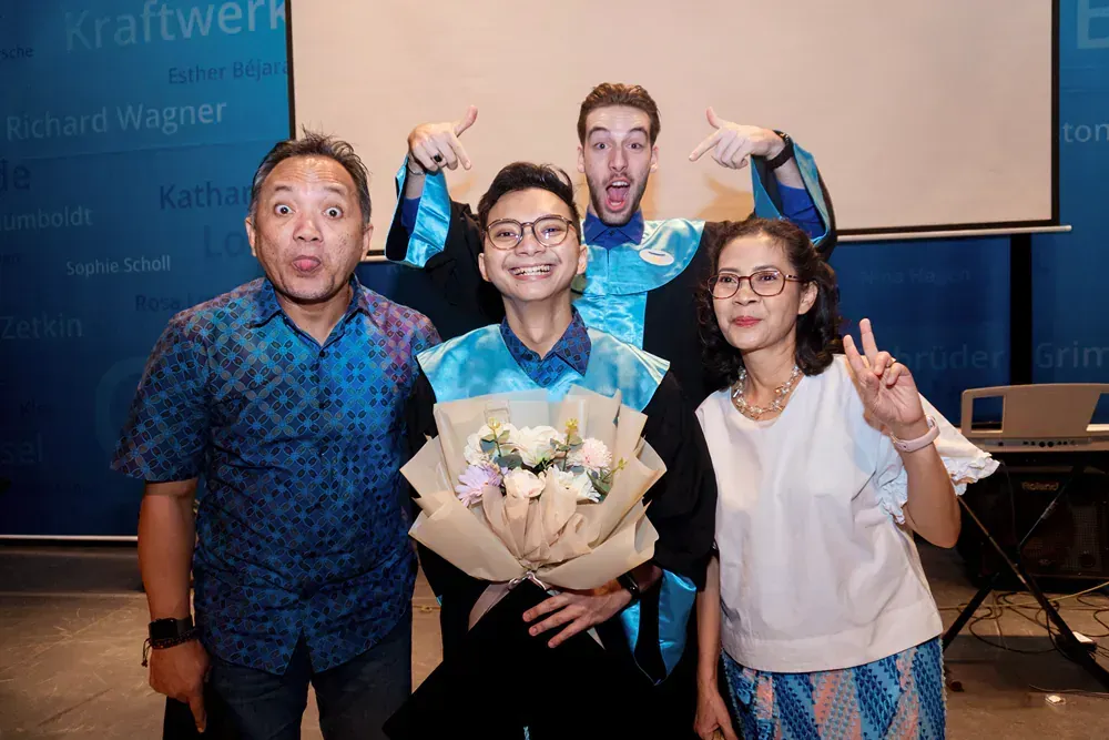 A group of people are posing for a picture with a man holding a bouquet of flowers.