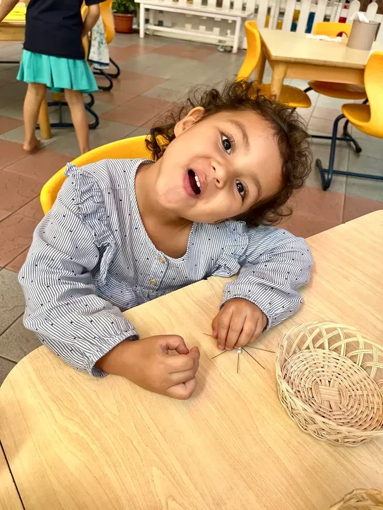 A little girl is sitting at a table with her mouth open.