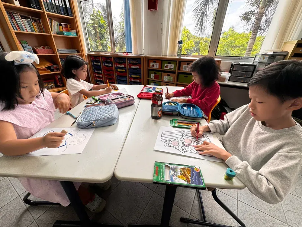 A group of children are sitting at a table in a classroom.
