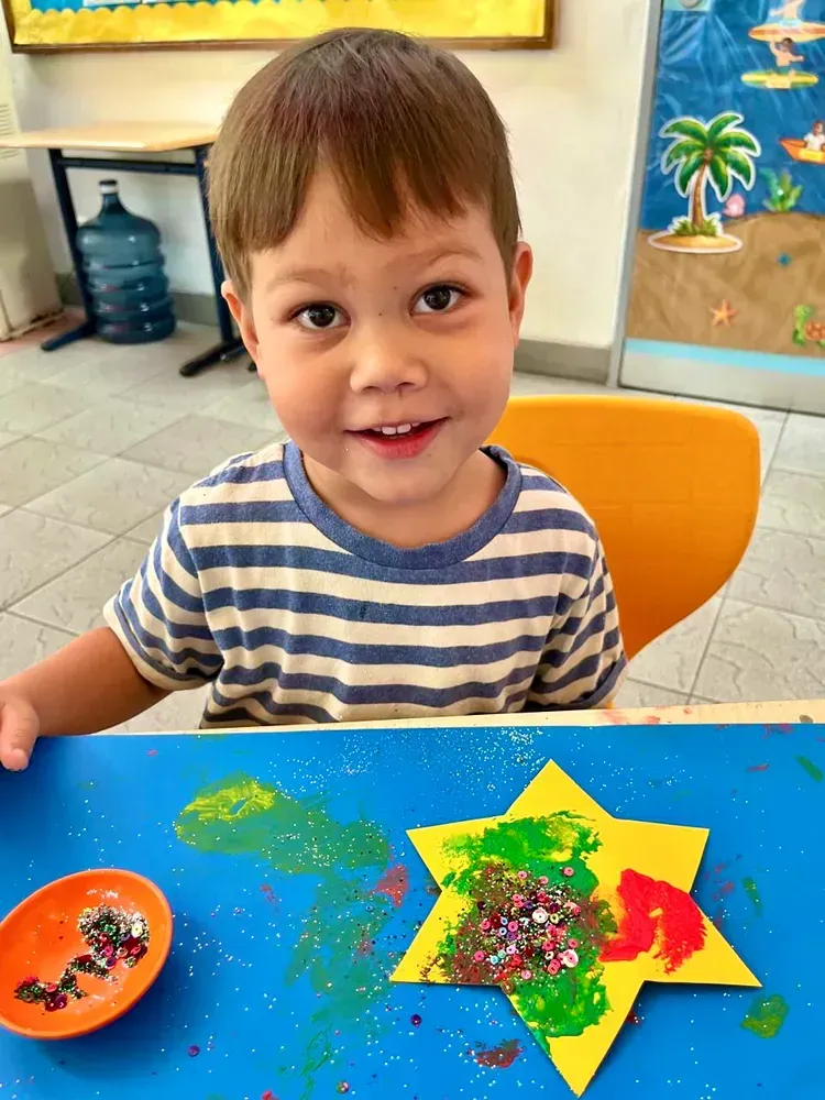 A little boy is sitting at a table with a star made out of paper