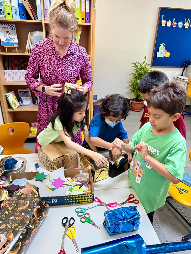 A group of children are sitting around a table with scissors.