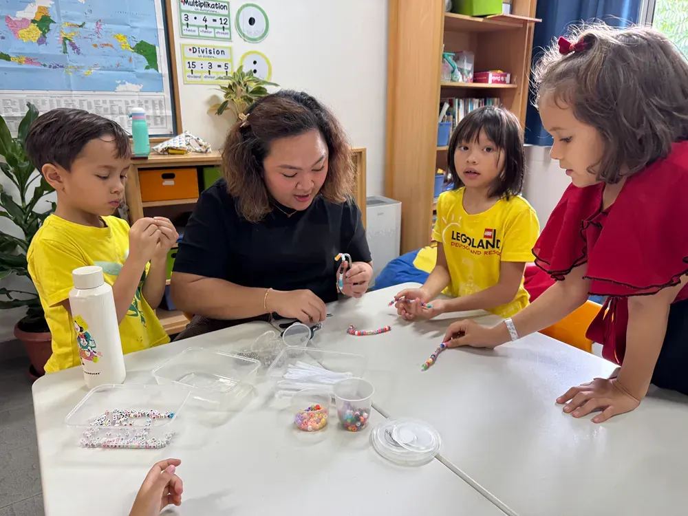 A group of children are sitting around a table with a woman.