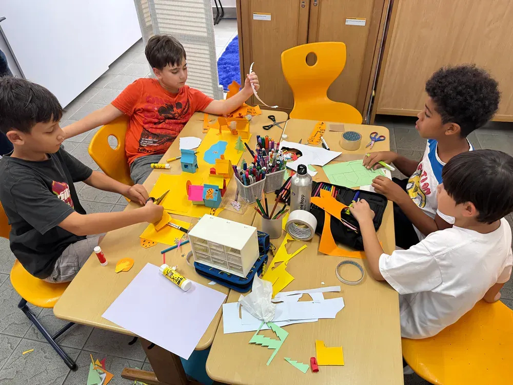 A group of young boys are sitting at a table making crafts.