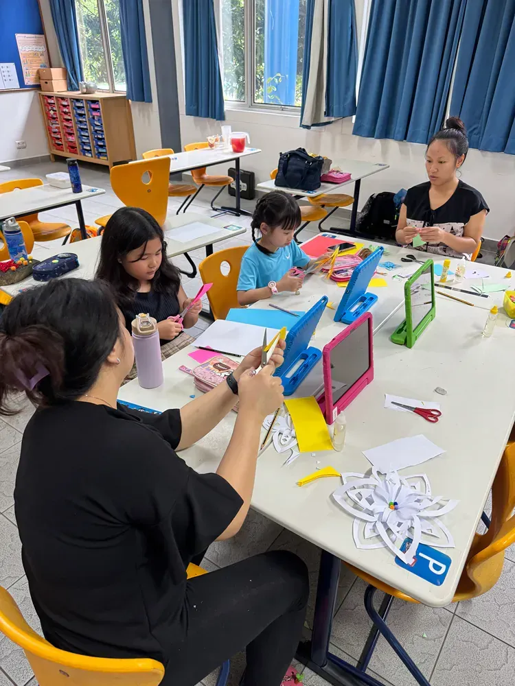 A group of children are sitting at tables in a classroom.