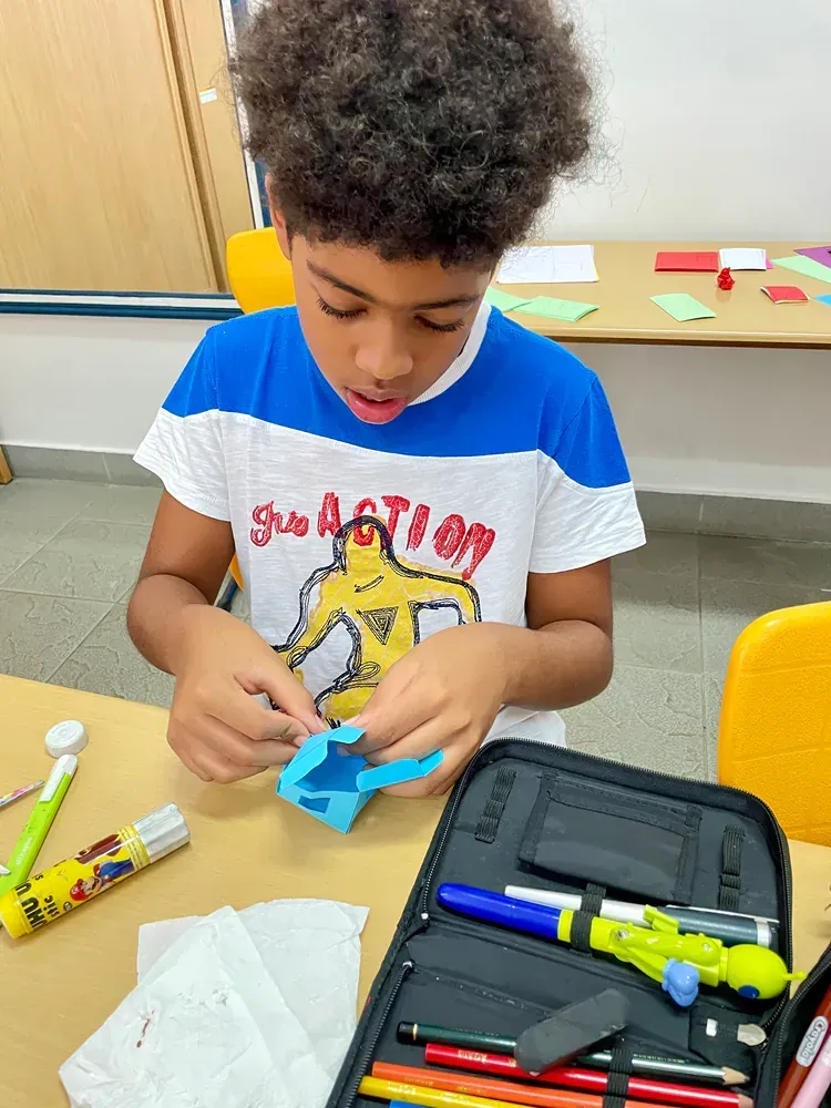 A young boy is sitting at a table making a craft.