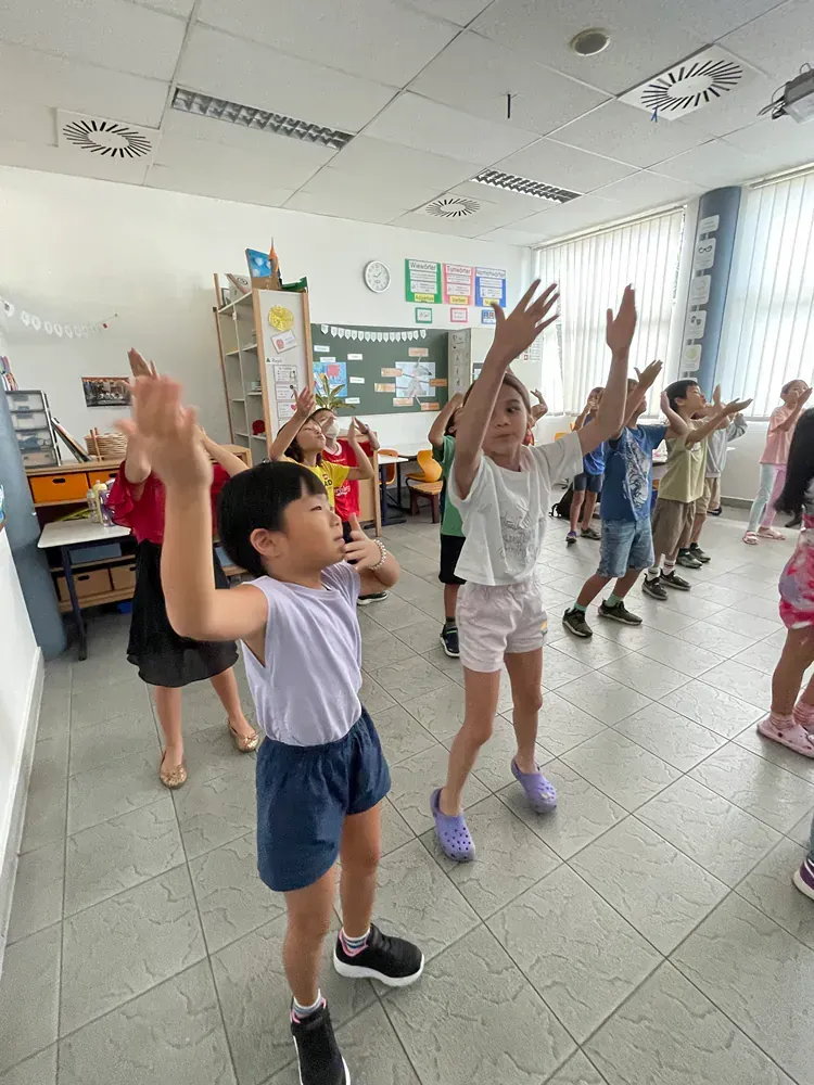 A group of children are dancing in a classroom.
