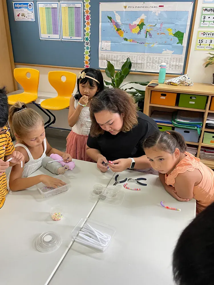 A group of young girls are sitting around a table in a classroom.