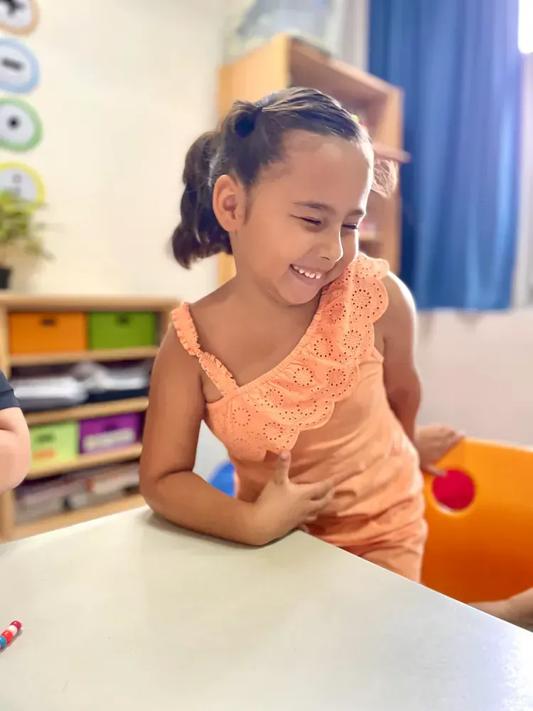 Smiling young girl in a peach dress engaged in a creative activity indoors.