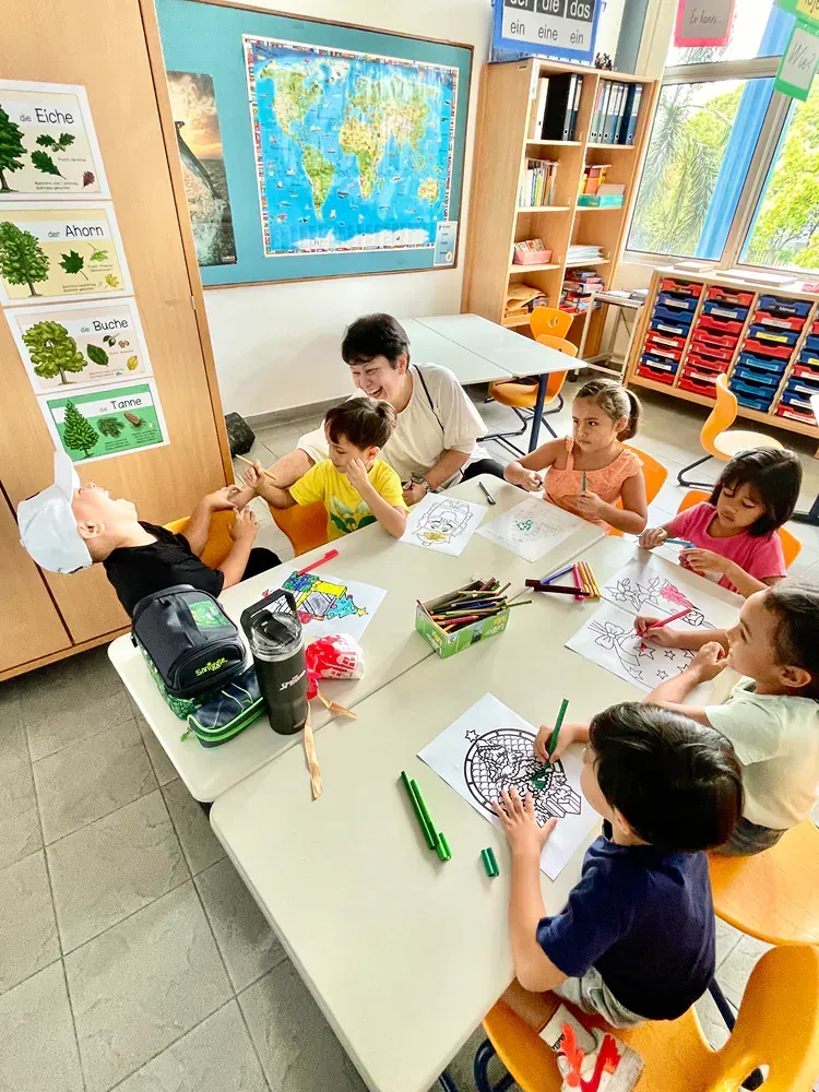 A group of children are sitting around a table in a classroom.
