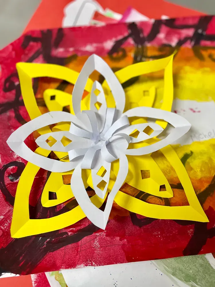 A paper flower is sitting on a red and yellow background