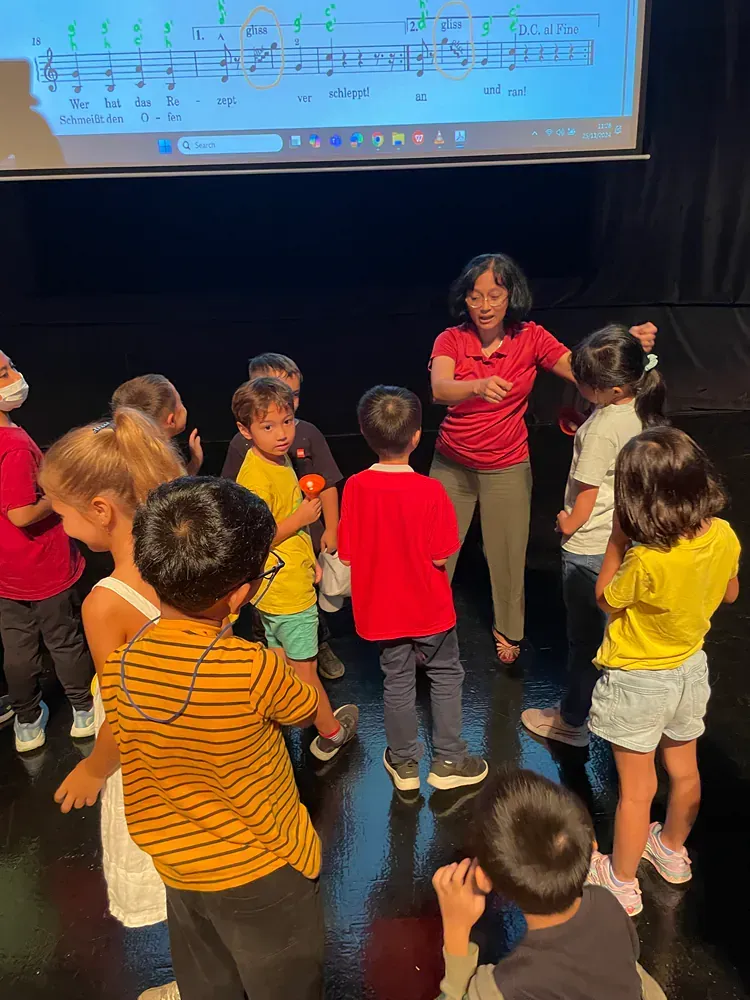 A woman is teaching a group of children how to play a musical instrument.